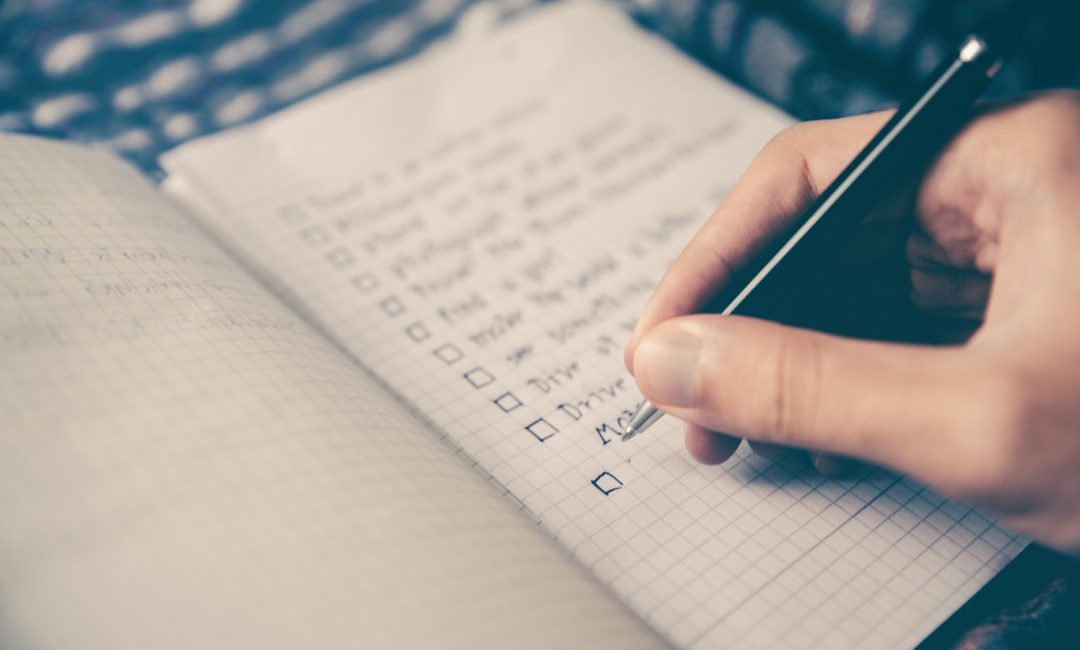 person writing bucket list on book