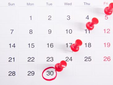 a calendar with red push buttons pinned to it