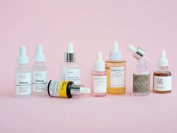 Skincare products are arranged on a pink background.